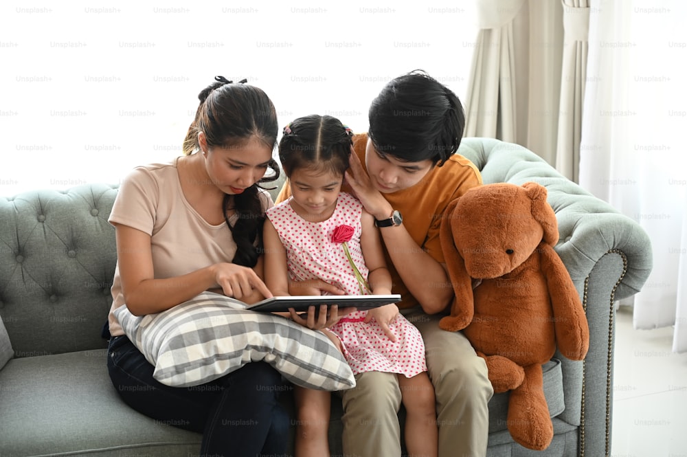 Los padres y un niño miran una computadora portátil en su tiempo libre en un fin de semana en una casa cómoda.