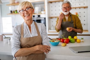 Senior couple having fun and cooking together in kitchen at home