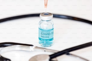 Vacuna contra el coronavirus con estetoscopio y jeringa al fondo
