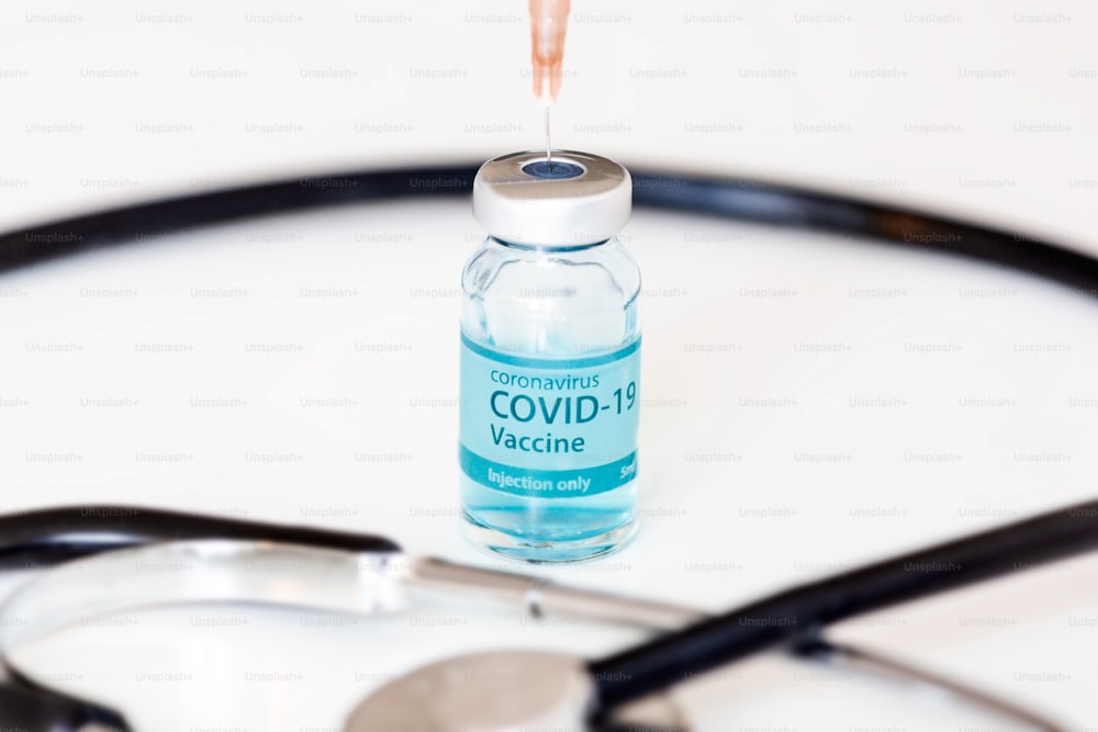 Coronavirus vaccine with stethoscope and syringe at the background