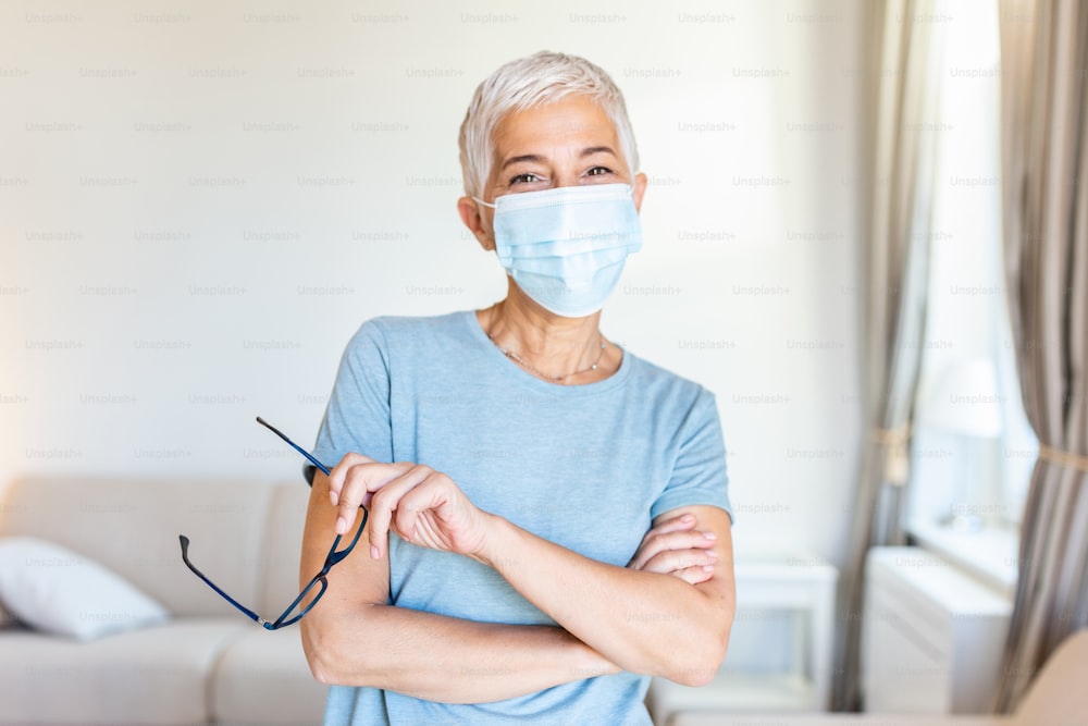 Senior woman in respiratory mask. Masked woman looks at camera. Cold, flu, virus, tonsillitis, respiratory disease, quarantine, epidemic concept.