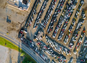 Vue aérienne de nombreux lots de vente aux enchères de voitures d’occasion garés dans un parking.