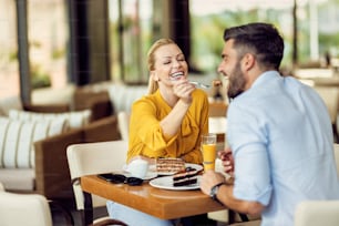 カフェで彼氏にケーキを食べさせながら楽しんでいる幸せな女性。