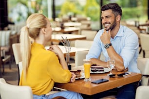 カフェでデザートを食べながらガールフレンドと話している幸せな男。