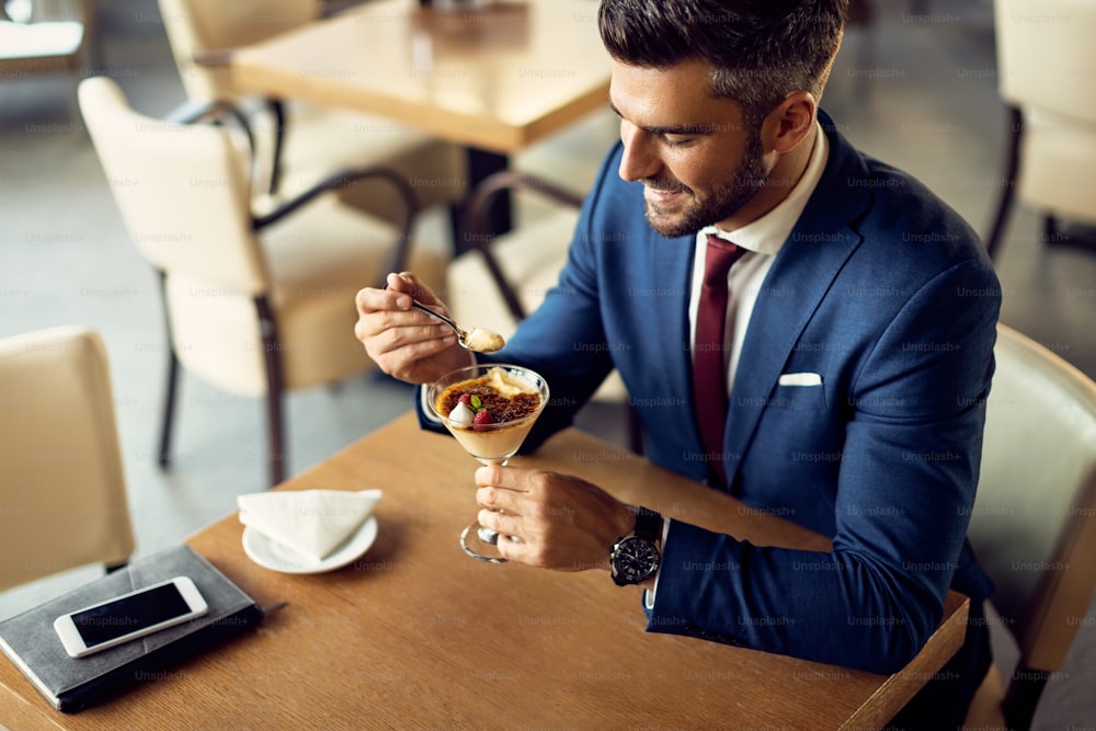 Empresário adulto médio comendo torta de limão com sorbet de framboesa enquanto comia sobremesa em um café,