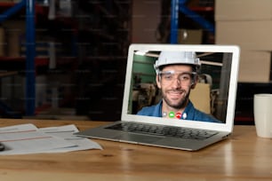 倉庫のコンピューター画面でビデオ通話で話す倉庫スタッフ。オンラインソフトウェア技術は、インターネットネットワーク上の仮想電話会議によって、物流工場で働く人々をつなぎます。