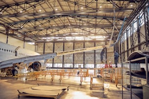 Portrait en pied d’ingénieurs aéronautiques debout sous l’aile avec un moteur à réaction dans une usine de maintenance d’avions