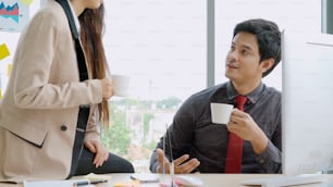 Two business people talk project strategy at office meeting room. Businessman discuss project planning with colleague at modern workplace while having conversation and advice on financial data report.