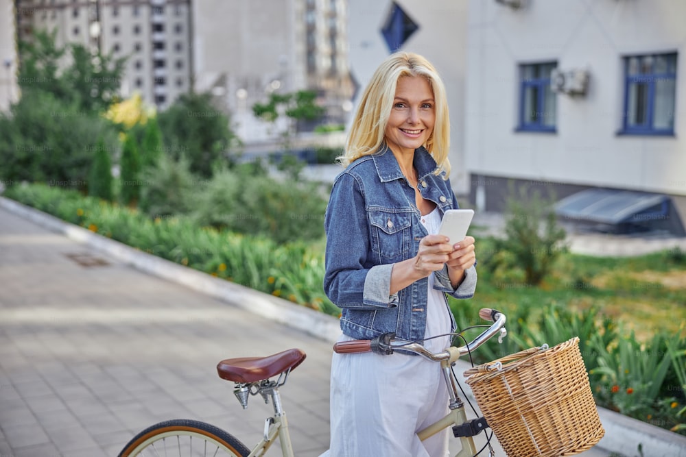 Retrato de cerca de una hermosa mujer bronceada con una bicicleta retro posando en la cámara de fotos al aire libre