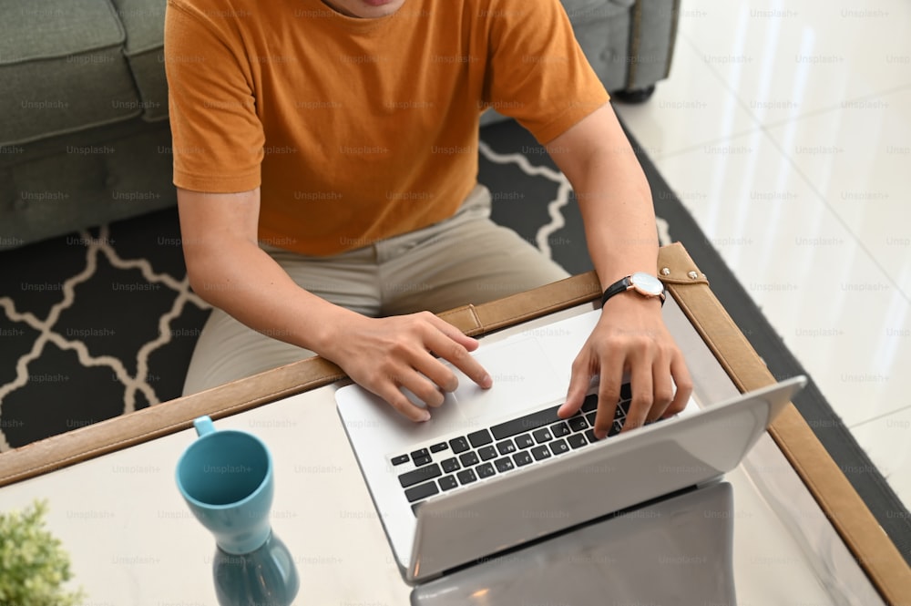 Foto recortada de un joven usando una computadora portátil en la sala de estar de su casa.