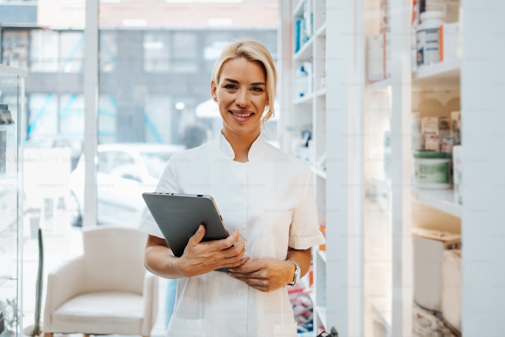 Young and attractive female pharmacist working in a drugstore. She is happy and smiled.