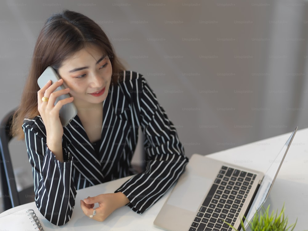 Top view of female office worker talking on the phone while sitting at office desk