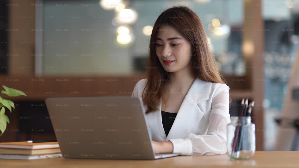 Cropped shot of young beautiful businesswoman typing on laptop computer in modern office room