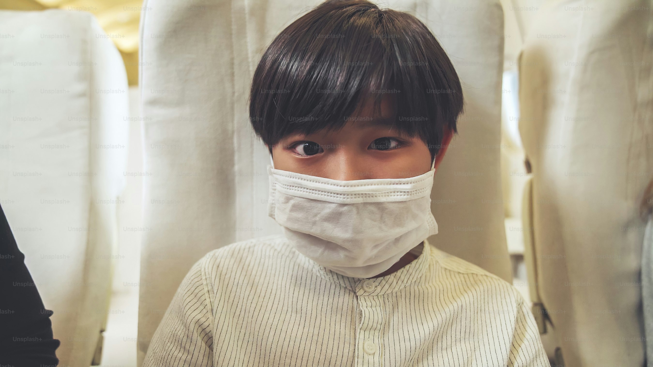 Traveler wearing face mask while traveling on commercial airplane . Concept of coronavirus disease or COVID 19 pandemic outbreak effects on tourism and airline business .