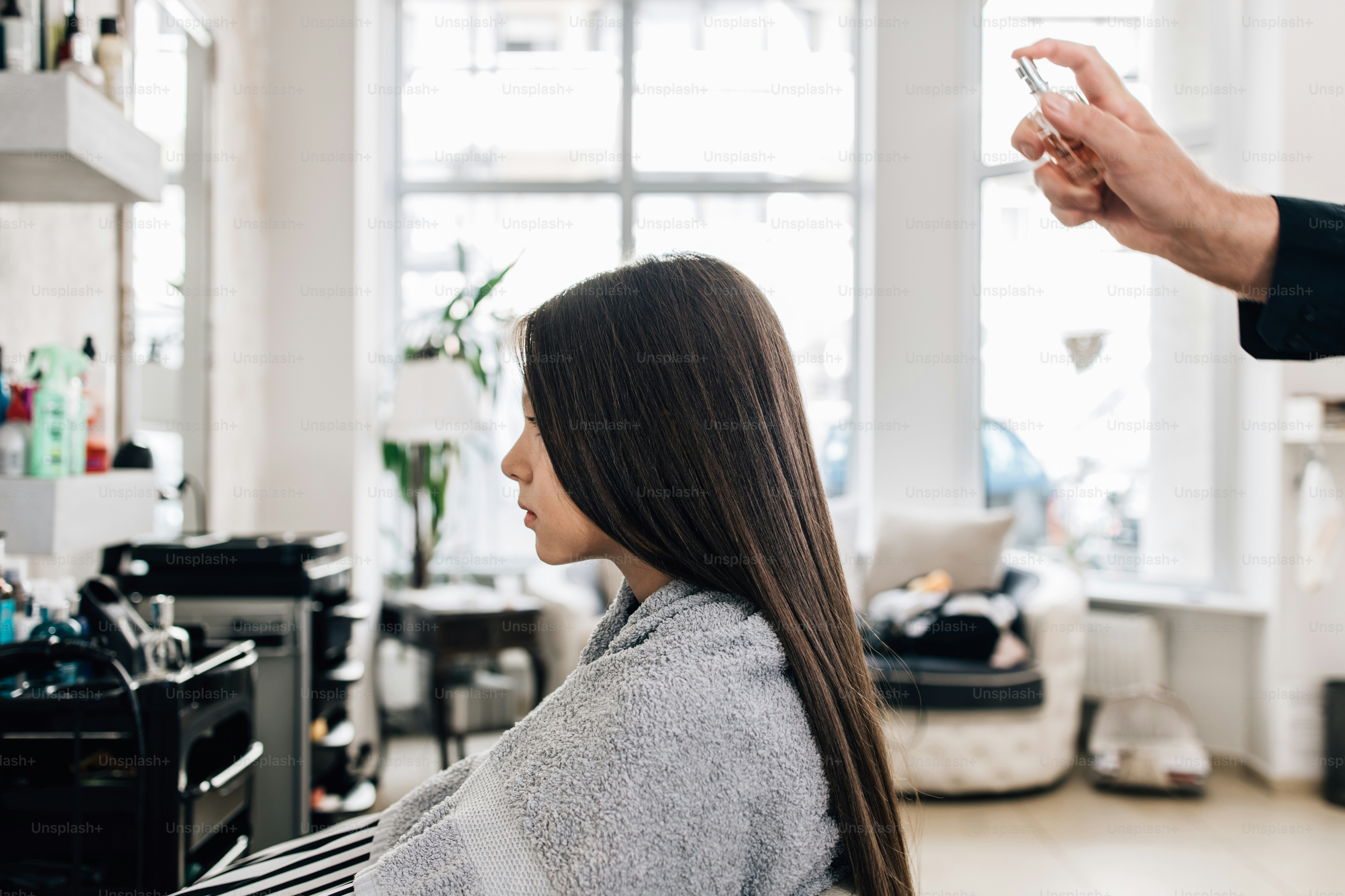 Giovane ragazza al trattamento dell'acconciatura mentre il parrucchiere professionista le lava delicatamente i capelli.