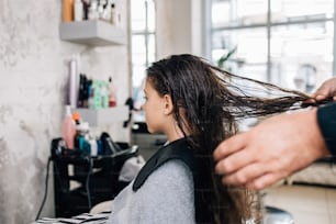 Jeune fille au traitement de coiffure tandis que le coiffeur professionnel se lave doucement les cheveux.