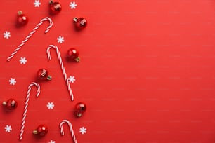 빨간 크리스마스 싸구려 장식, 사탕 지팡이, 빨간색 배경에 색종이. 플랫 레이, 평면도, 복사 공간. 새해 인사말 카드 모형, 배너 템플릿입니다.
