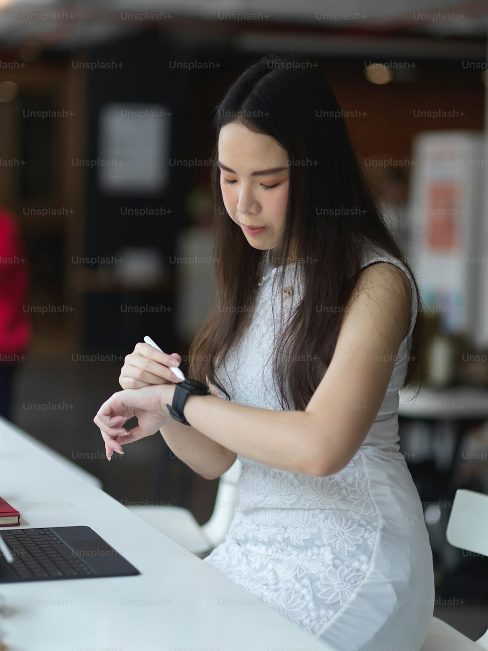 Retrato da fêmea olhando no smartwatch enquanto trabalha no espaço de coworking