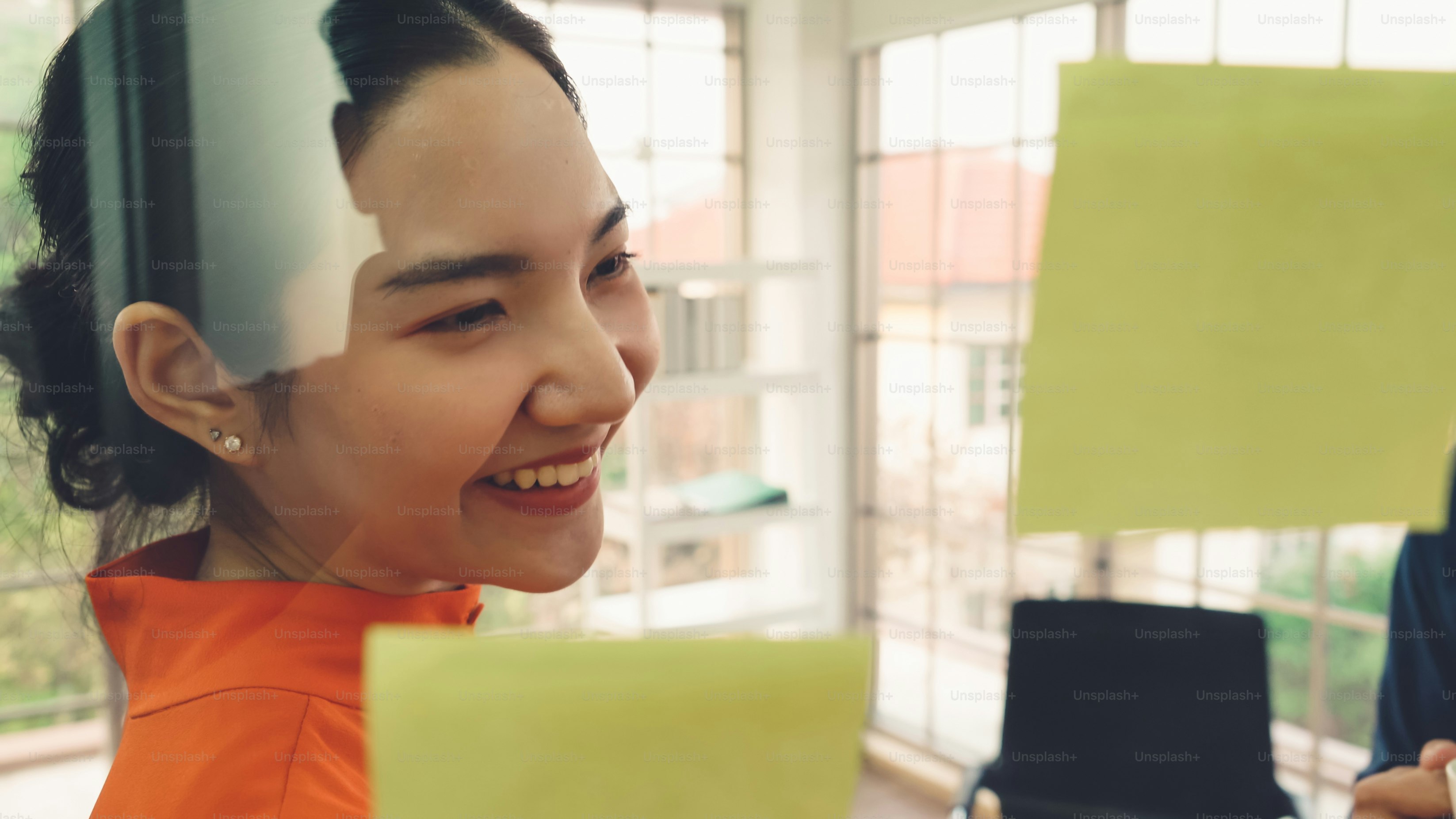 Business people work on project planning board in office and having conversation with coworker friend to analyze project development . They use sticky notes posted on glass wall to make it organized .