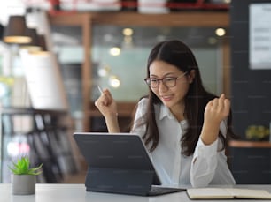 Portrait of cheerful female office worker looking on digital tablet in office room