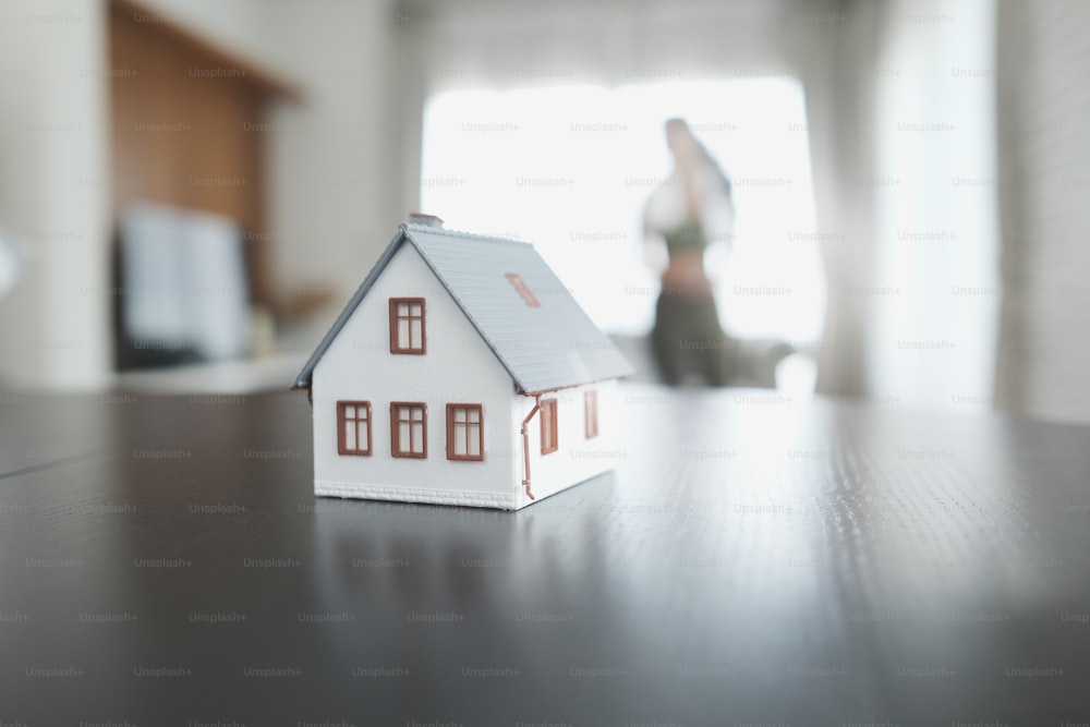 A house model on the black wooden table with blur living room background.