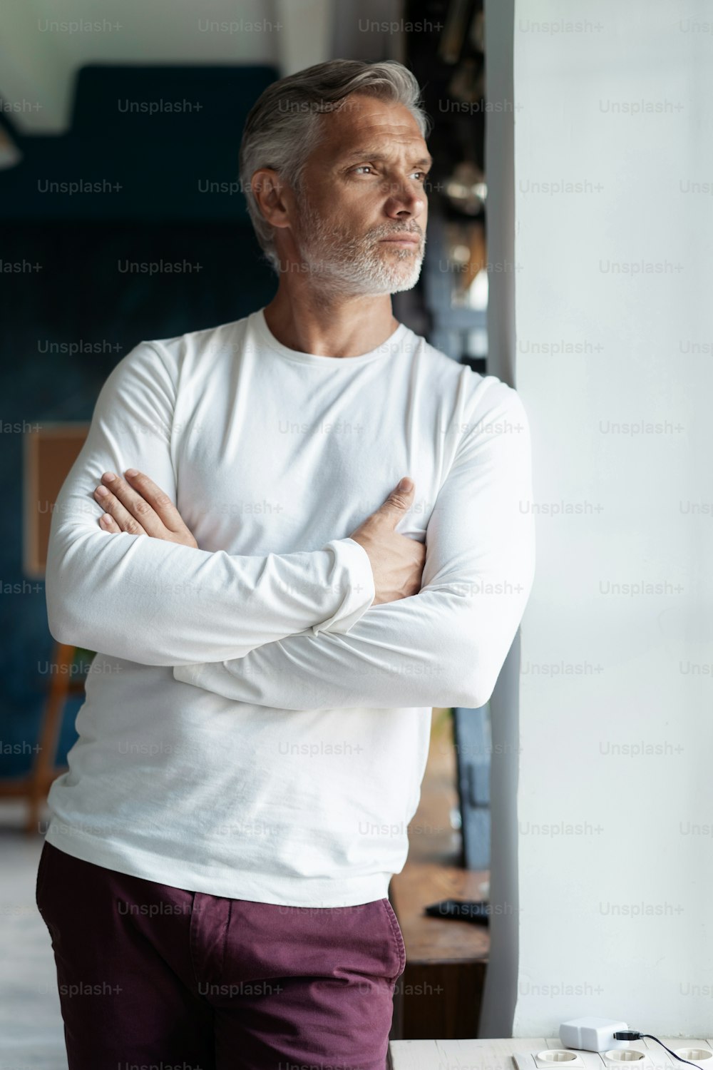 Business lifestyle. Casual Grey-haired Mature professional handsome businessman standing near window in his office while thinking about his goals