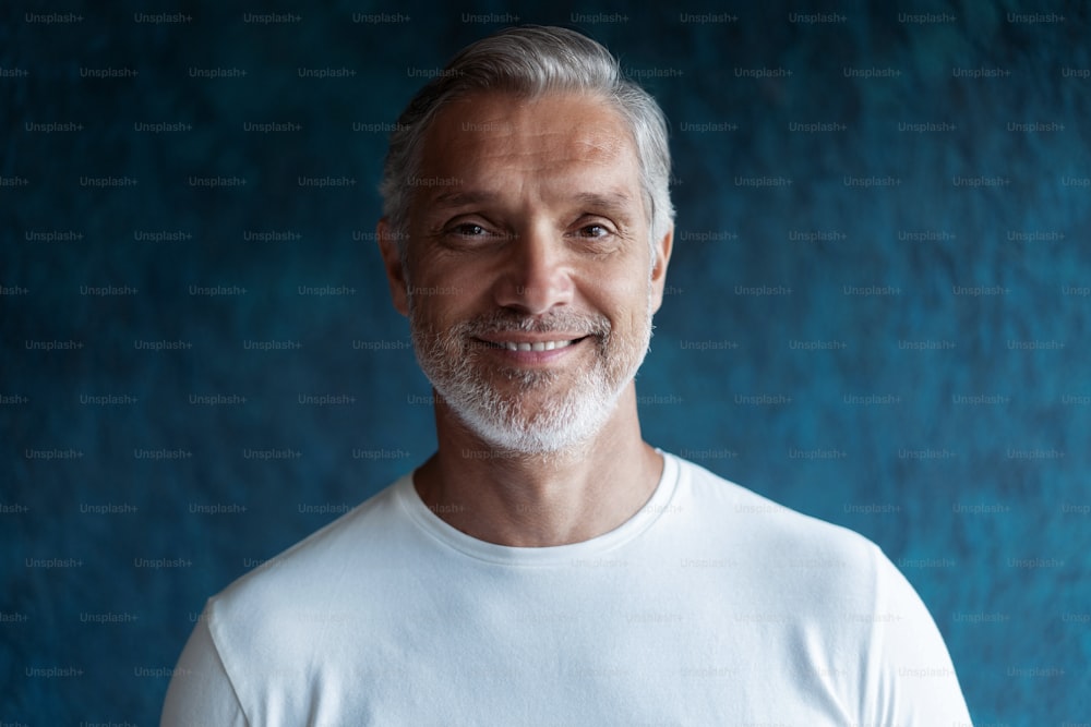 Casual Grey-haired Mature handsome man portrait over dark blue wall background