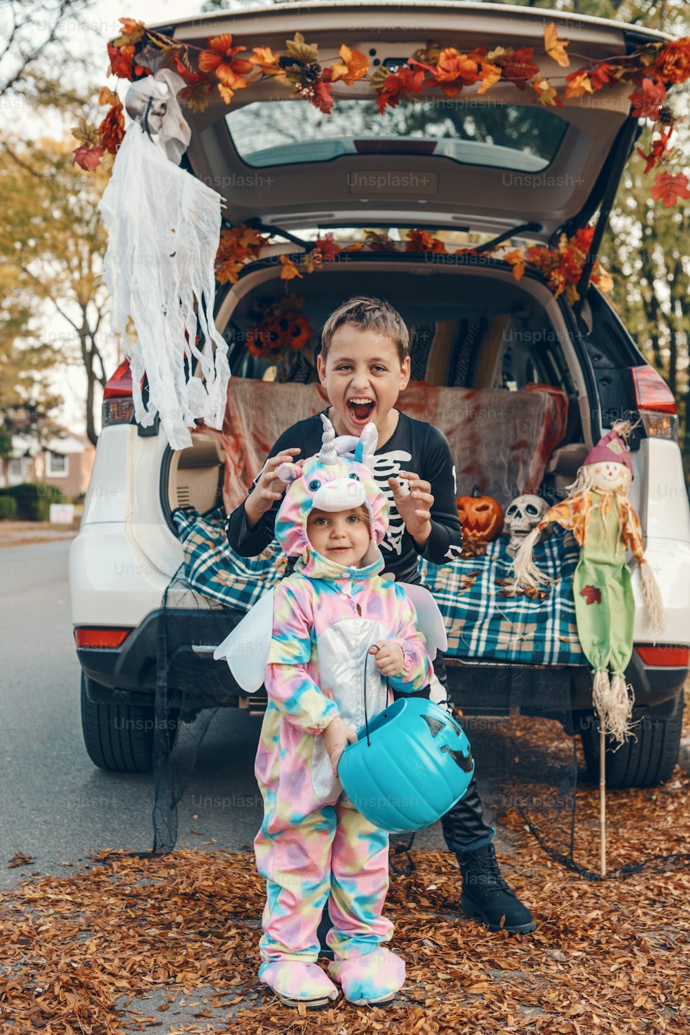 Trick o trunk. Siblings brother and sister celebrating Halloween in trunk of car. Children kids boy and baby girl celebrating October holiday outdoor. Social distance and safe alternative celebration