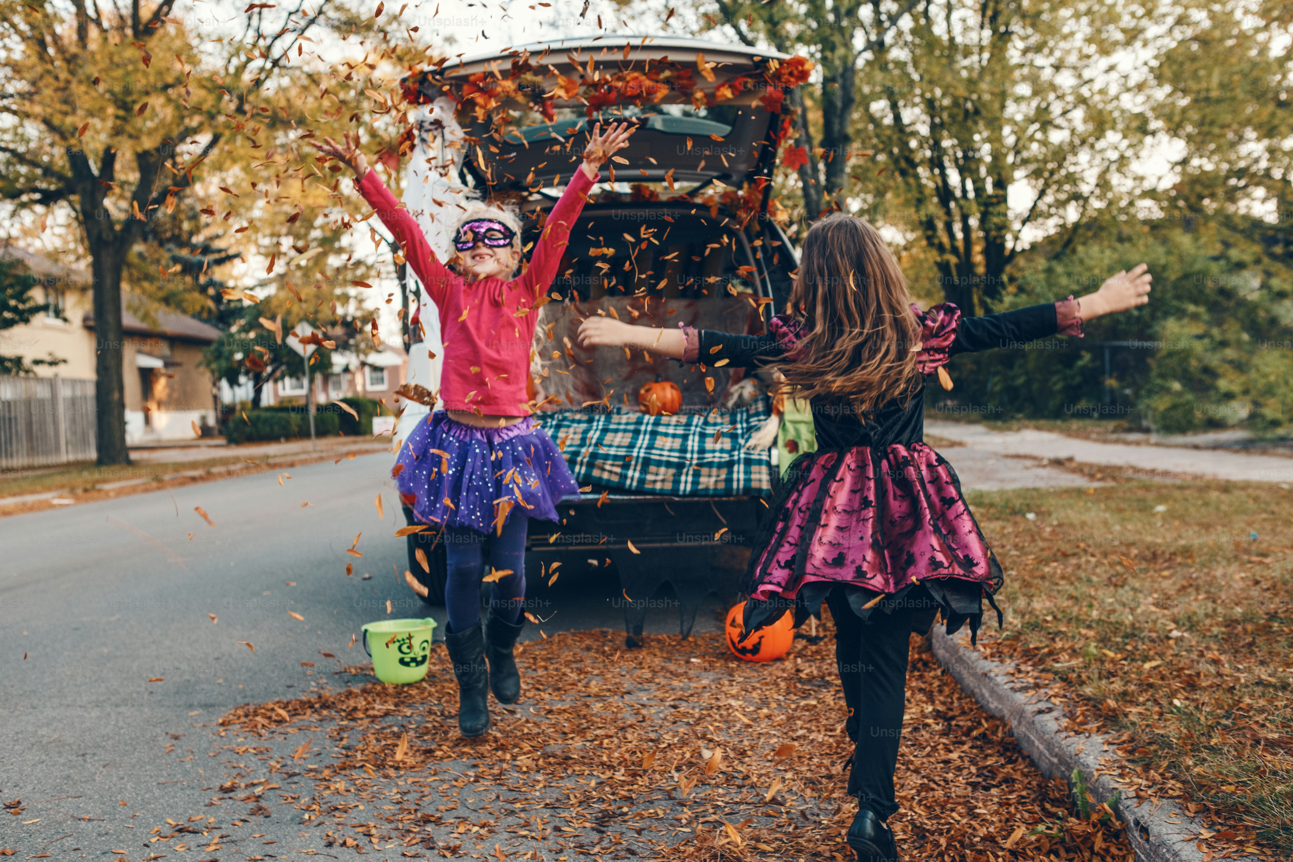 Trick or trunk. Children siblings sisters celebrating Halloween in trunk of car. Friends kids girls preparing for October holiday outdoor. Social distance and safe alternative celebration.