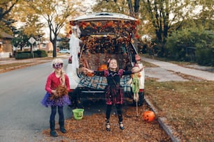 Trucco o tronco. Bambini, fratelli, sorelle, che festeggiano Halloween nel bagagliaio dell'auto. Amici, bambini, ragazze, che si preparano per le vacanze di ottobre all'aperto. Distanziamento sociale e celebrazione alternativa sicura.