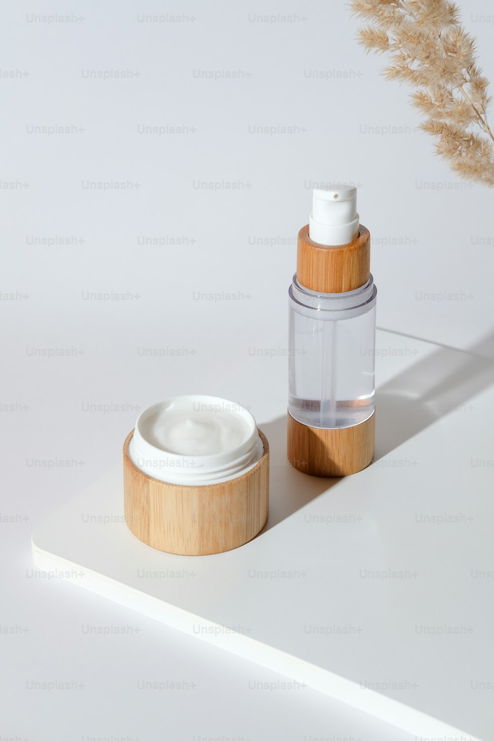 Jar of natural organic cream moisturizer and lotion on white podium with dried flowers. Eco-friendly bamboo cosmetics packaging