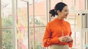 Business people work on project planning board in office and having conversation with coworker friend to analyze project development . They use sticky notes posted on glass wall to make it organized .