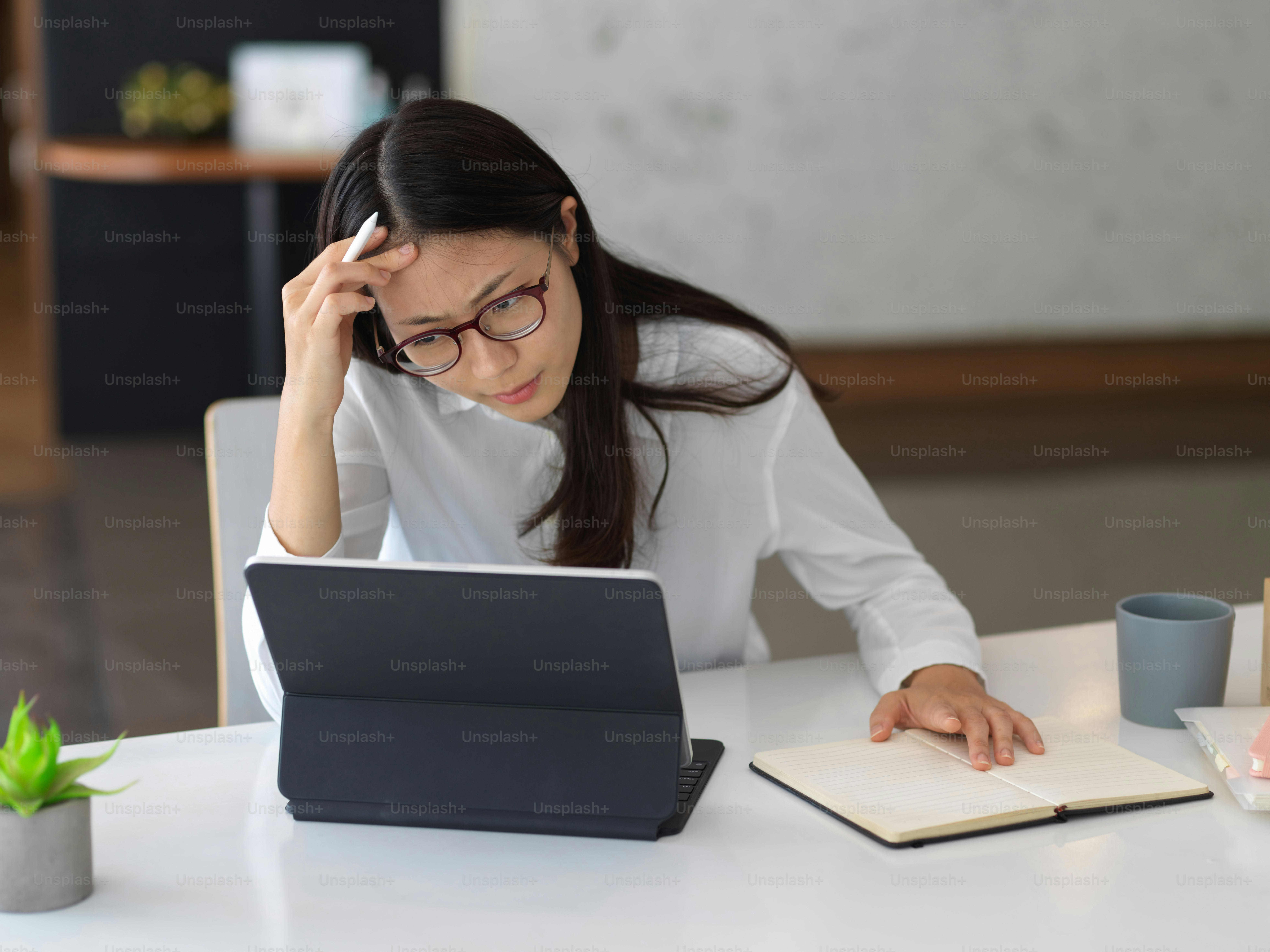 Serious young businesswoman focusing on her project while working on her tablet in office room