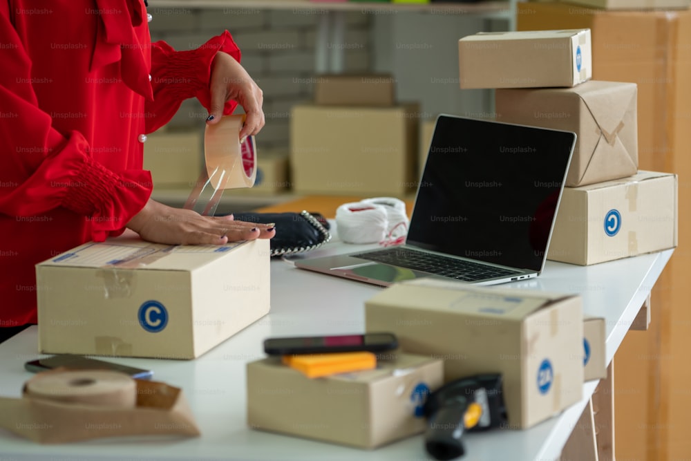 オンライン販売者はホームオフィスで働き、顧客に配送ボックスを梱包します。インターネット上で電子商取引ビジネスを行う中小企業の経営者または起業家。