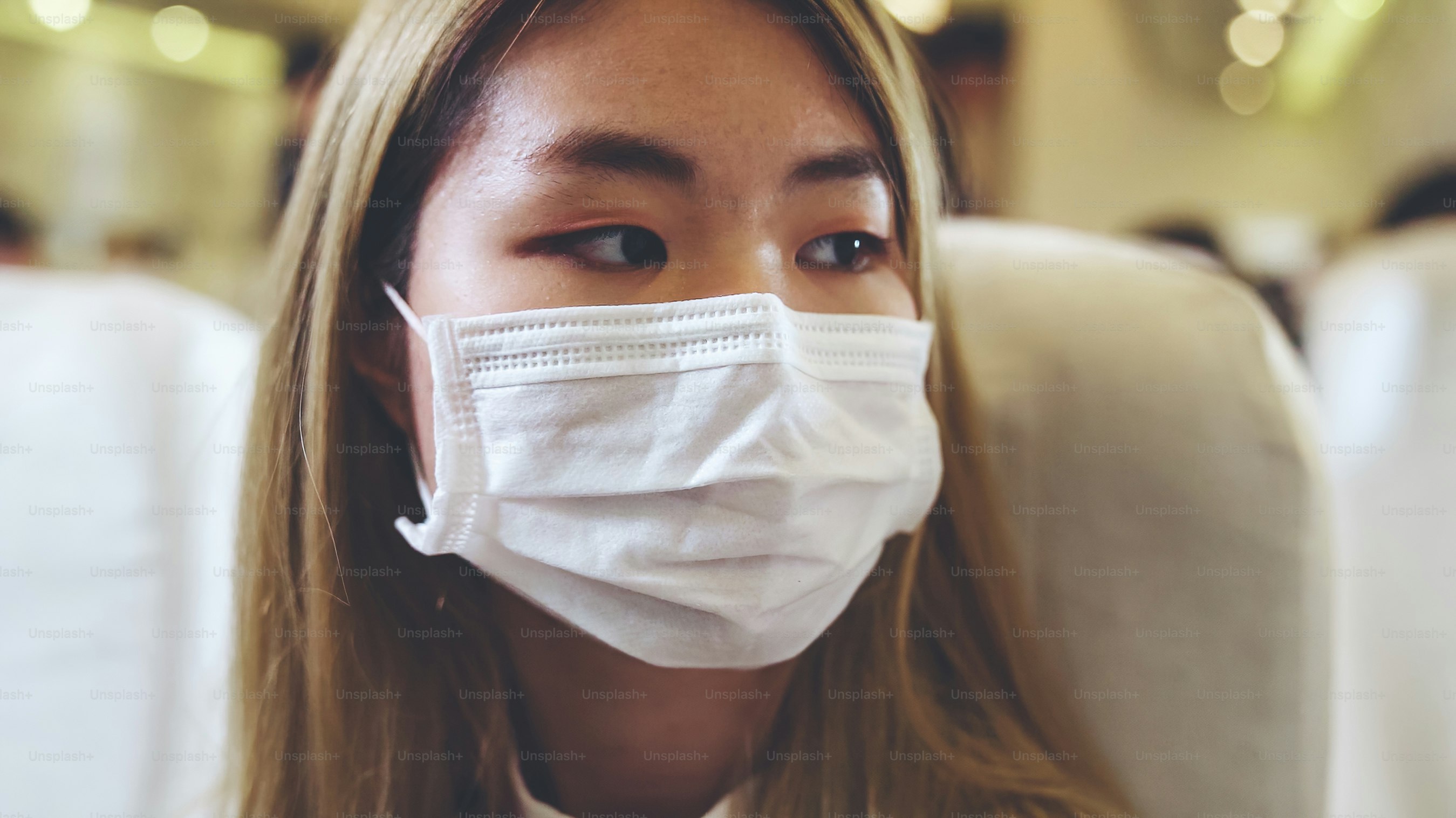 Traveler wearing face mask while traveling on commercial airplane . Concept of coronavirus disease or COVID 19 pandemic outbreak effects on tourism and airline business .