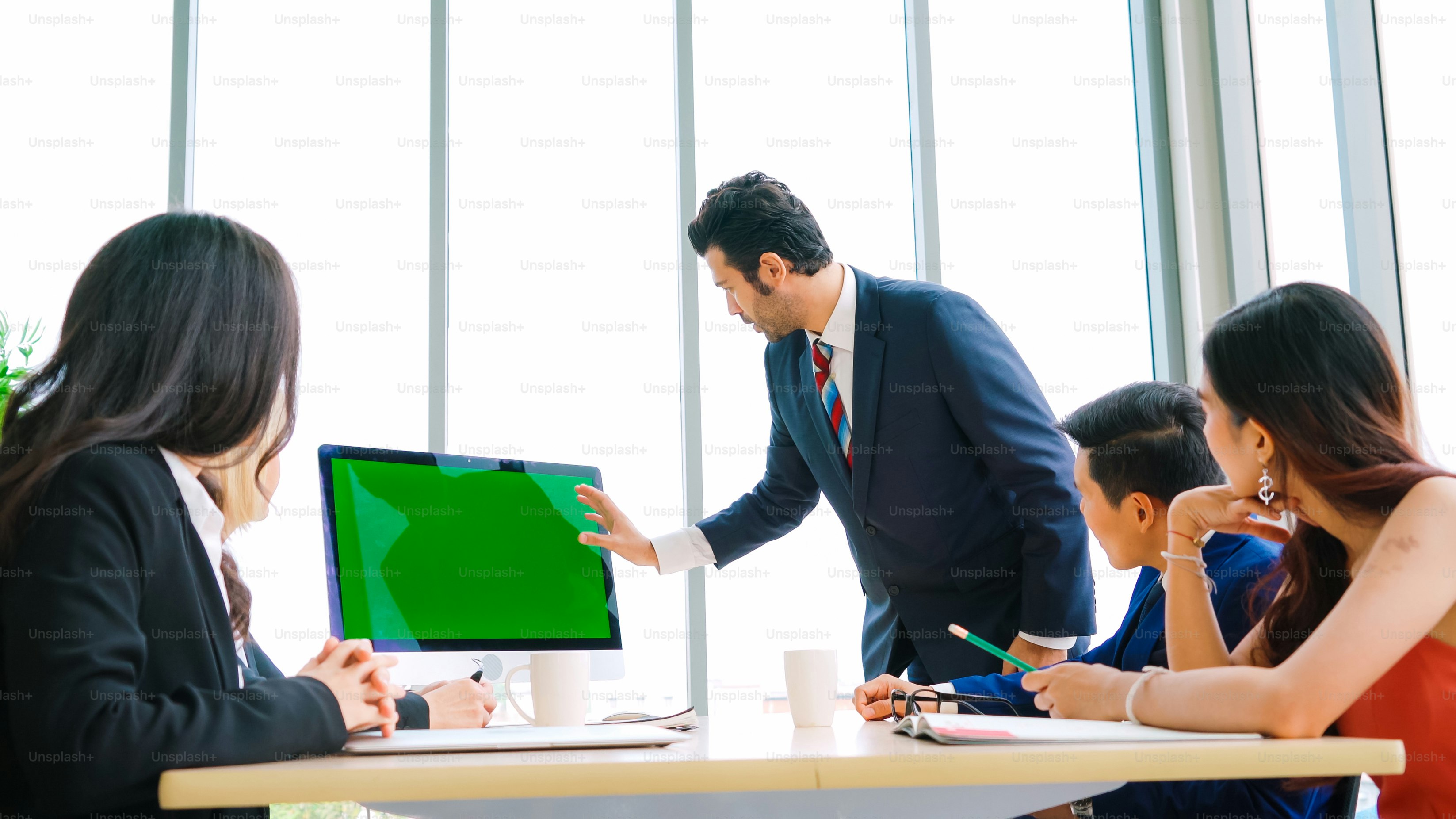 Uomini d'affari nella sala conferenze con schermo verde chroma key TV o computer sul tavolo dell'ufficio. Gruppo eterogeneo di uomo d'affari e donna d'affari in riunione in videoconferenza.