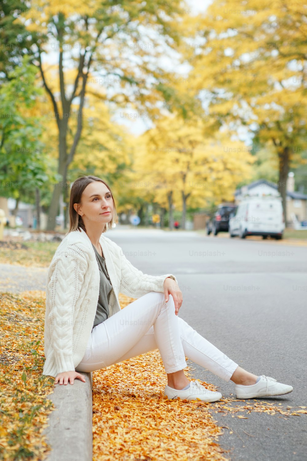 Bella donna caucasica di mezza età con i capelli corti seduta in autunno autunno strada all'aperto. Giovane donna con taglio di capelli corto in abiti casual nel parco all'esterno. Piccoli momenti memorabili di vita.