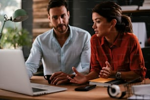 Businessman and businesswoman in office. Two friends drinking coffee while working on the project