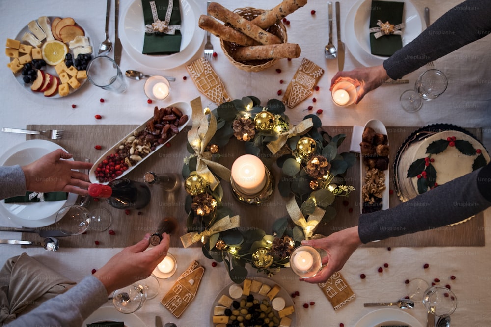 Midsection of unrecognizable couple indoors at home setting the table at Christmas, top view.
