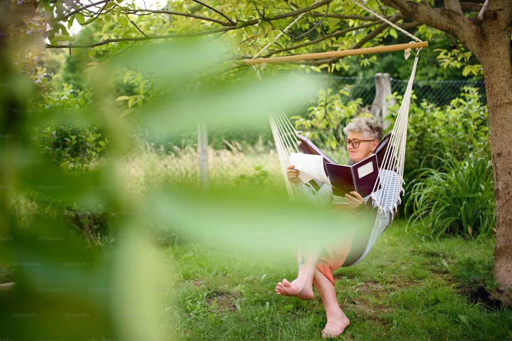 Front view portrait of active senior woman working outdoors in garden, home office concept.