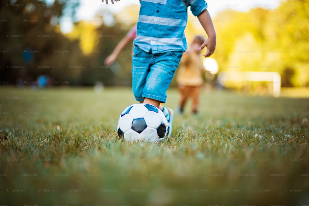 Football player.  Little boy boy playing football alone on the grass. Focus is on legs.