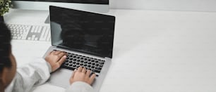 Vue latérale des mains féminines à l’aide d’une maquette de tablette numérique sur un bureau d’ordinateur dans un bureau.