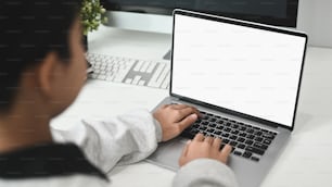 Cropped shot of female hands typing on laptop keyboard with on white table.