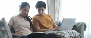 Young couple relaxing together on a sofa with a laptop computer surfing the internet.