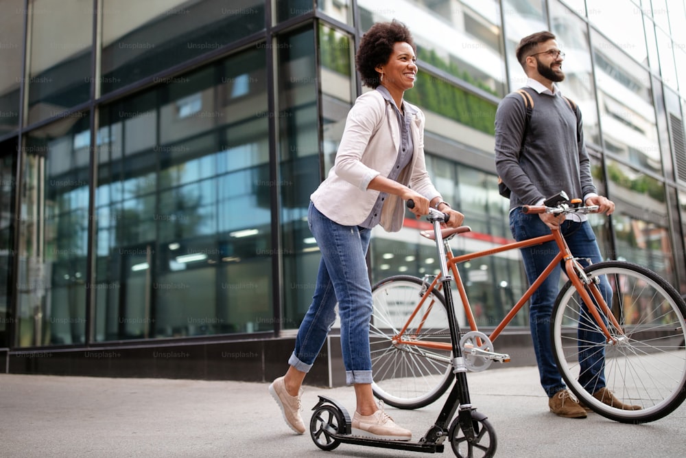 Glückliches interrassisches Paar mit Elektroroller, Fahrrad in der Stadt. Grünes Öko-Energiekonzept emissionsfrei