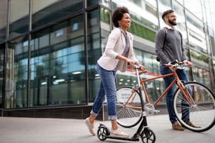 Happy interracial couple using electric scooter, bicycle in city. Green eco energy concept with zero emission