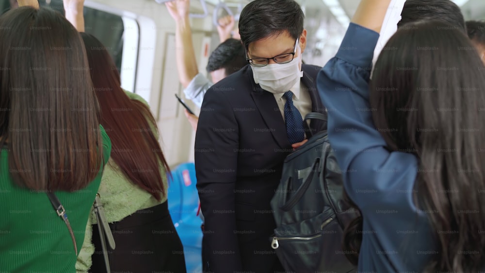 Junger Mann mit Gesichtsmaske fährt in überfüllter U-Bahn. Coronavirus-Krankheit oder COVID-19-Pandemie-Ausbruch und städtisches Lebensstilproblem im Berufsverkehrskonzept.