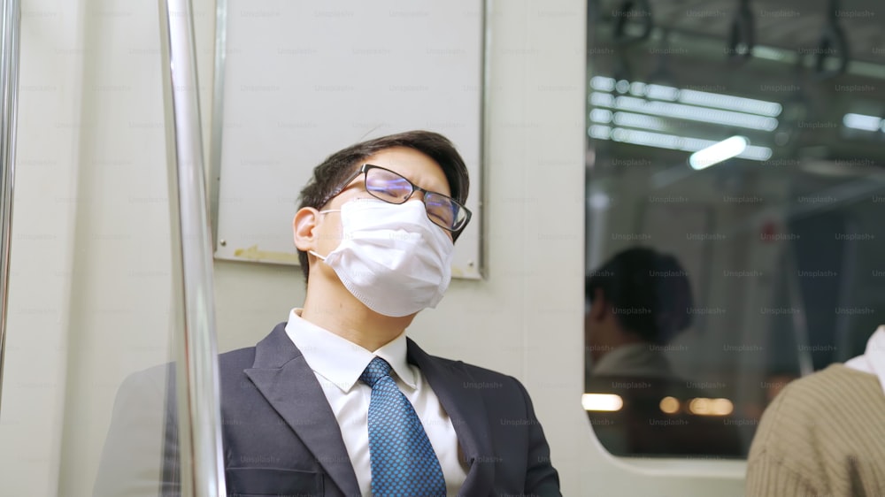 Young man wearing face mask travels on crowded subway train . Coronavirus disease or COVID 19 pandemic outbreak and urban lifestyle problem in rush hour concept .