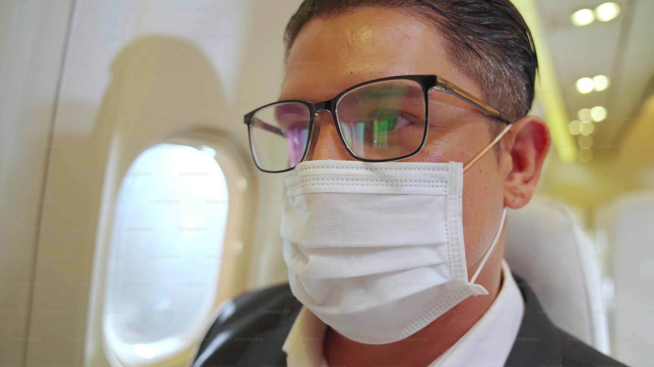 Traveler wearing face mask while traveling on commercial airplane . Concept of coronavirus disease or COVID 19 pandemic outbreak effects on tourism and airline business .
