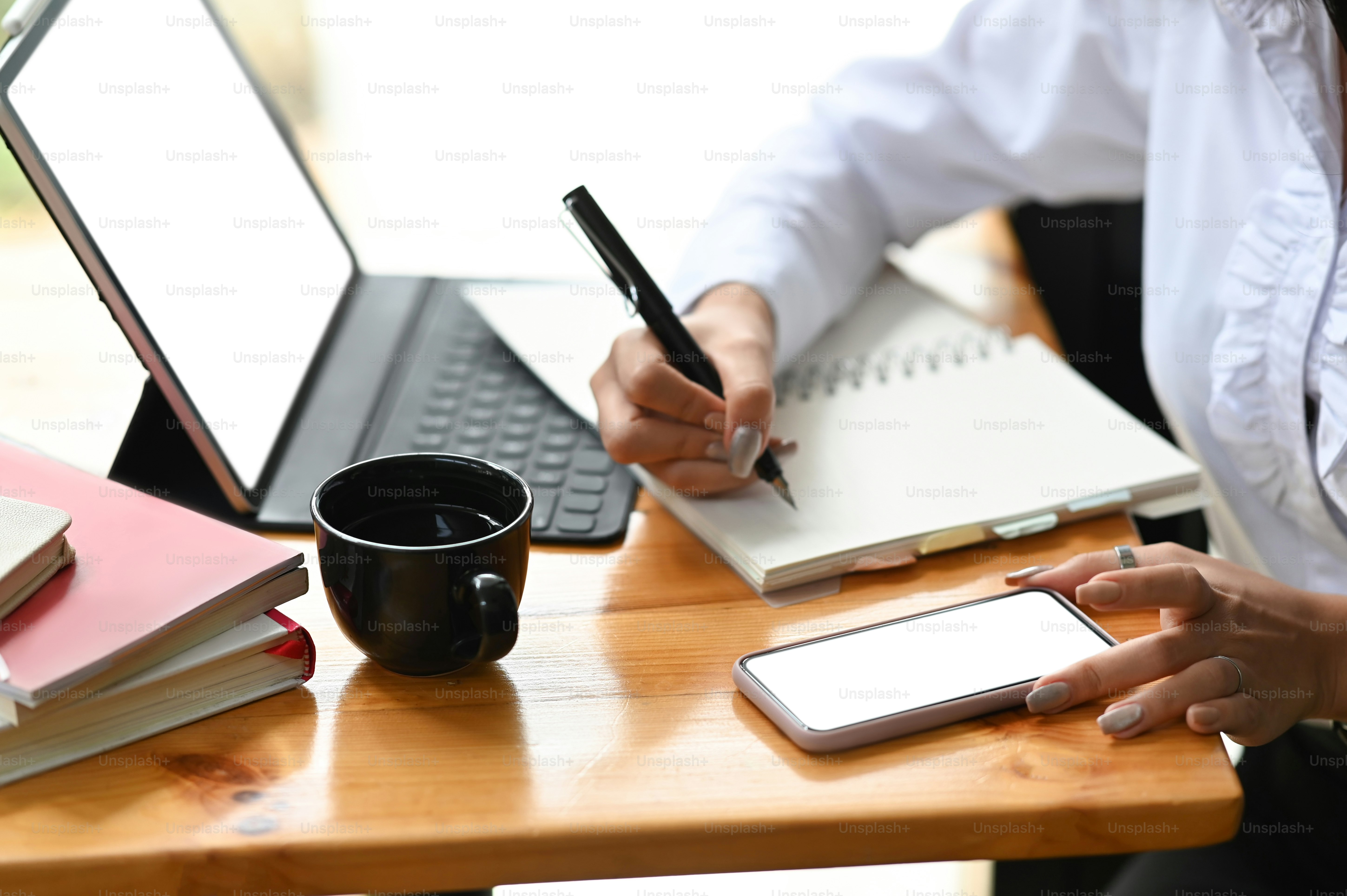 Cropped shot of female worker sitting at worktable with clipping path tablet and taking note in office.